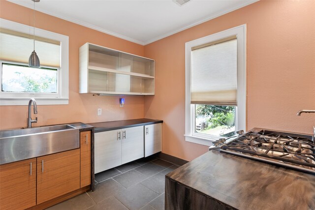 2616 45th St, Galveston, TX 77550 - kitchen featuring a sink, dark countertops, dark tile patterned flooring, crown molding, and hanging light fixtures