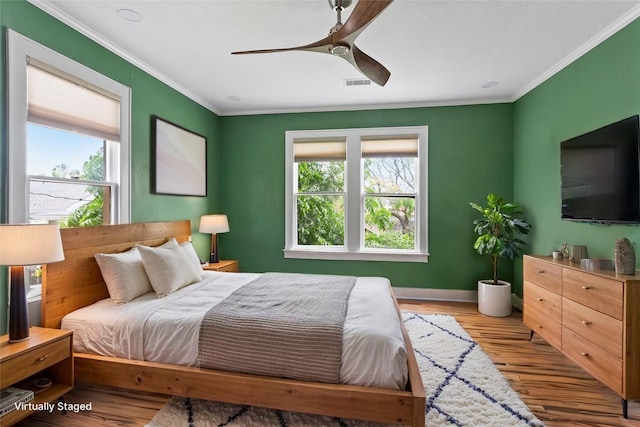 2616 45th St, Galveston, TX 77550 - bedroom featuring multiple windows, crown molding, wood finished floors, ceiling fan, and baseboards