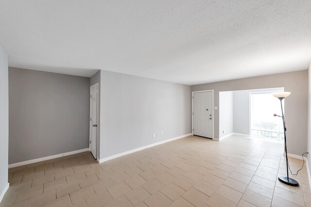 12633 Memorial Dr Unit 179, Houston, TX 77024 - spare room with light tile patterned floors, baseboards, and a textured ceiling