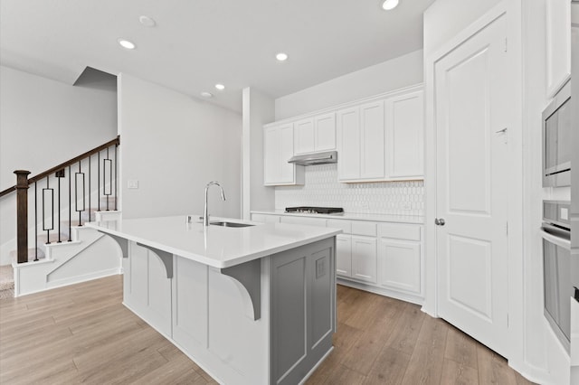 16514 Lake Austin St, Cypress, TX 77433 - kitchen with stainless steel appliances, under cabinet range hood, light wood-type flooring, light countertops, and an island with sink