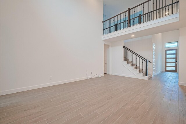 30351 Spragletop View St, Brookshire, TX 77423 - unfurnished living room featuring a high ceiling, stairs, light wood finished floors, and baseboards