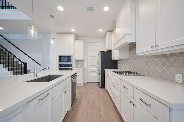 30351 Spragletop View St, Brookshire, TX 77423 - kitchen featuring a sink, appliances with stainless steel finishes, white cabinets, light countertops, and decorative light fixtures