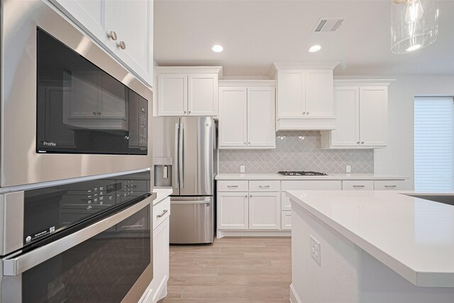 30351 Spragletop View St, Brookshire, TX 77423 - kitchen featuring appliances with stainless steel finishes, white cabinetry, light wood-type flooring, light countertops, and tasteful backsplash