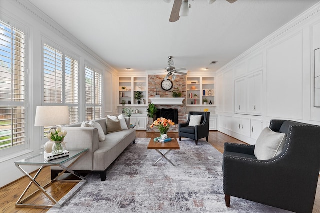 20234 Brondesbury Dr, Katy, TX 77450 - living area with ceiling fan, wood finished floors, built in shelves, a fireplace, and ornamental molding