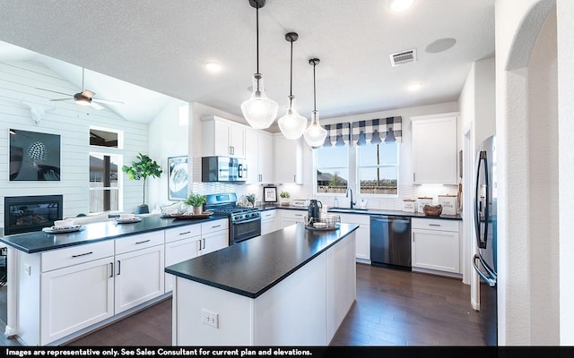 12106 Hollow Marsh Dr, Santa Fe, TX 77510 - kitchen featuring stainless steel appliances, dark countertops, dark wood-style flooring, a kitchen island, and vaulted ceiling
