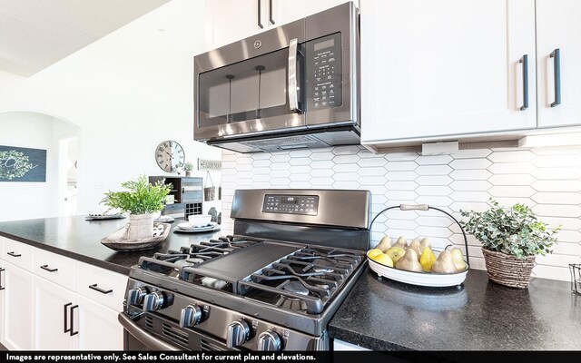 12106 Hollow Marsh Dr, Santa Fe, TX 77510 - kitchen featuring appliances with stainless steel finishes, dark countertops, white cabinetry, tasteful backsplash, and arched walkways
