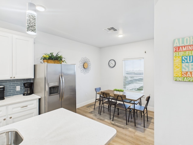 2403 S Bronte St, Rockport, TX 78382 - kitchen featuring stainless steel refrigerator with ice dispenser, light countertops, light wood-style floors, and white cabinets