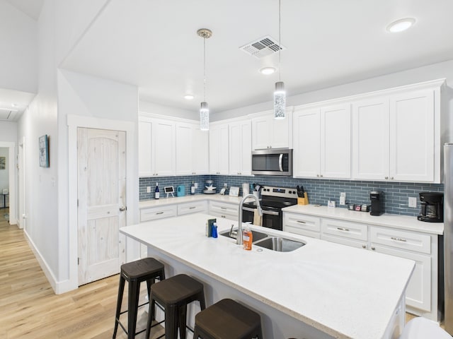 2403 S Bronte St, Rockport, TX 78382 - kitchen featuring appliances with stainless steel finishes, a sink, backsplash, light countertops, and a breakfast bar