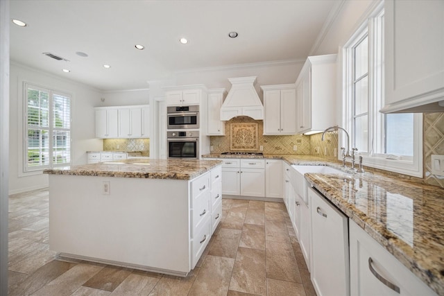 10918 Wickline Dr, Hunters Creek Village, TX 77024 - kitchen featuring custom range hood, a kitchen island, crown molding, white cabinetry, and appliances with stainless steel finishes