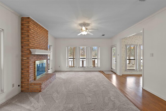 1925 E Lake Dr, Huntsville, TX 77340 - unfurnished living room with a ceiling fan, ornamental molding, a brick fireplace, wood finished floors, and carpet flooring