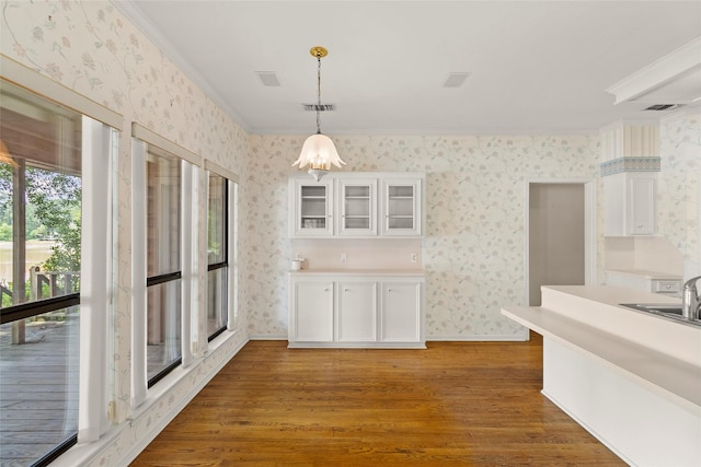 1925 E Lake Dr, Huntsville, TX 77340 - kitchen with wallpapered walls, crown molding, wood finished floors, white cabinets, and glass insert cabinets