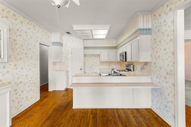 1925 E Lake Dr, Huntsville, TX 77340 - kitchen featuring stainless steel microwave, stove, wood finished floors, a peninsula, and wallpapered walls