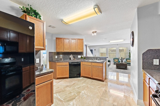 11622 Silent Elm St, Houston, TX 77044 - kitchen featuring black appliances, decorative backsplash, a textured ceiling, a sink, and a peninsula