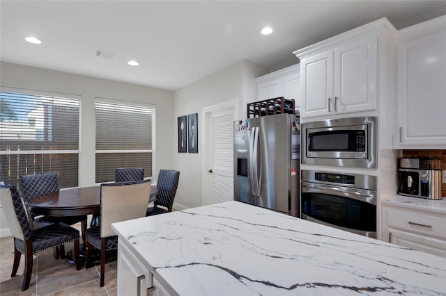6003 Tarra Firma Dr, Spring, TX 77379 - kitchen with appliances with stainless steel finishes, light stone countertops, white cabinetry, recessed lighting, and light tile patterned flooring