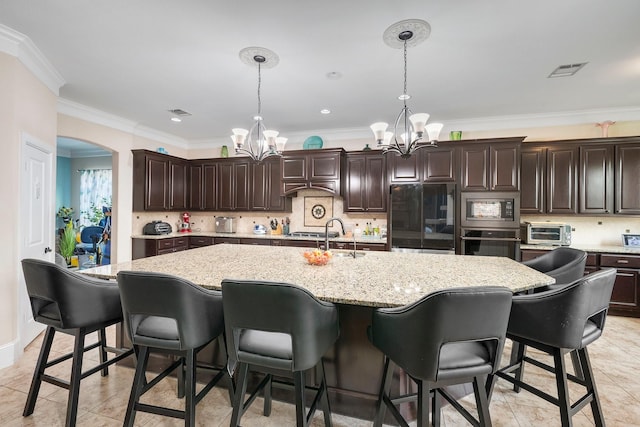 4314 Hadleigh Ln, College Station, TX 77845 - kitchen featuring stainless steel appliances, a chandelier, ornamental molding, pendant lighting, and an island with sink