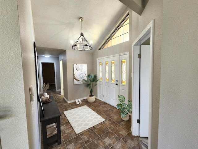 482 W Cattle Dr, Onalaska, TX 77360 - foyer with a chandelier, a textured wall, high vaulted ceiling, baseboards, and dark stone finish flooring
