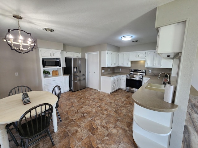 482 W Cattle Dr, Onalaska, TX 77360 - kitchen with appliances with stainless steel finishes, a sink, a chandelier, dark stone finish floors, and white cabinets