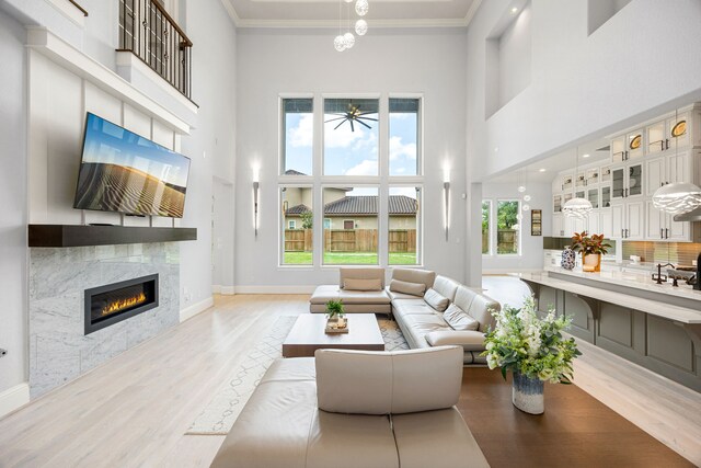 19111 N Frio River Cir, Cypress, TX 77433 - living room featuring a high ceiling, wood finished floors, a fireplace, ornamental molding, and a ceiling fan