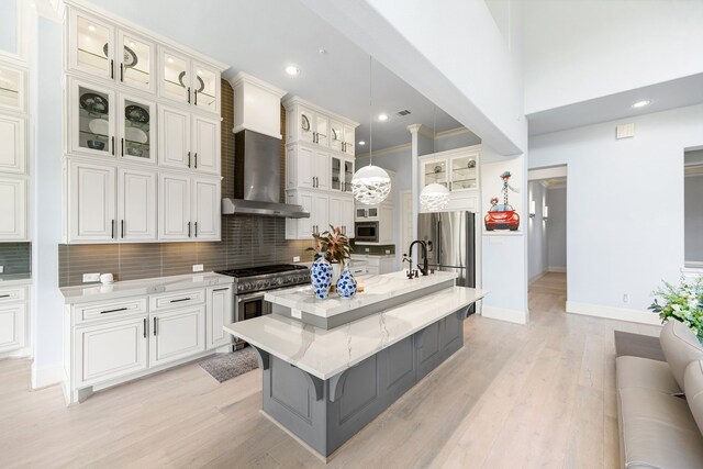 19111 N Frio River Cir, Cypress, TX 77433 - kitchen featuring appliances with stainless steel finishes, decorative backsplash, a large island, baseboards, and wall chimney exhaust hood