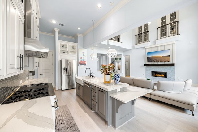 19111 N Frio River Cir, Cypress, TX 77433 - kitchen featuring appliances with stainless steel finishes, ornamental molding, a sink, open floor plan, and under cabinet range hood