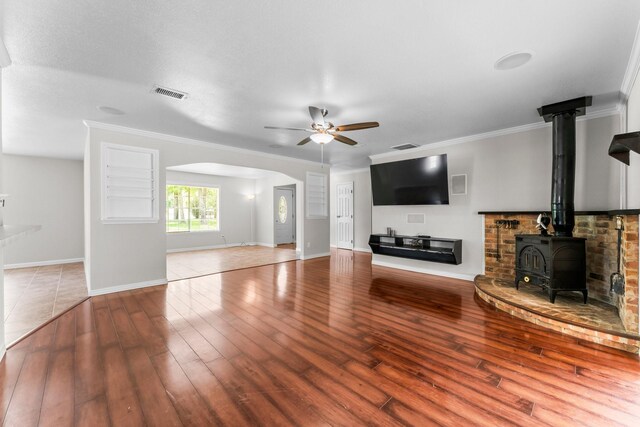 31614 Debbi Ln, Magnolia, TX 77355 - unfurnished living room featuring arched walkways, a wood stove, ceiling fan, wood finished floors, and baseboards