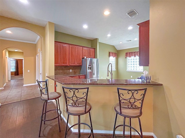 1314 Varese Dr, Pearland, TX 77581 - kitchen with stainless steel fridge with ice dispenser, recessed lighting, a peninsula, arched walkways, and a breakfast bar area