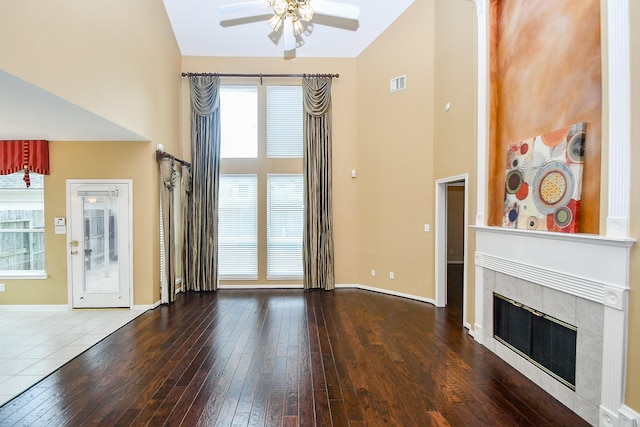 1623 Heddon Falls Dr, Sugar Land, TX 77479 - unfurnished living room featuring a ceiling fan, high vaulted ceiling, a tiled fireplace, hardwood / wood-style floors, and baseboards