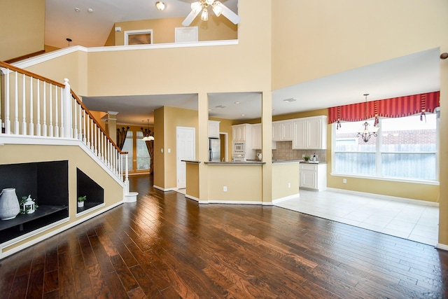 1623 Heddon Falls Dr, Sugar Land, TX 77479 - unfurnished living room featuring wood-type flooring, a ceiling fan, stairs, a towering ceiling, and baseboards
