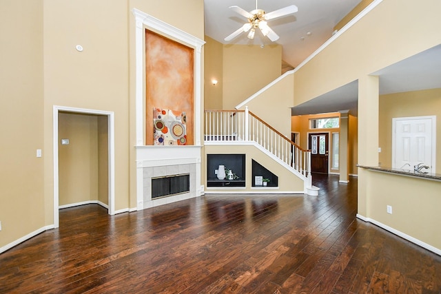 1623 Heddon Falls Dr, Sugar Land, TX 77479 - unfurnished living room featuring a towering ceiling, wood-type flooring, stairway, a ceiling fan, and a tiled fireplace