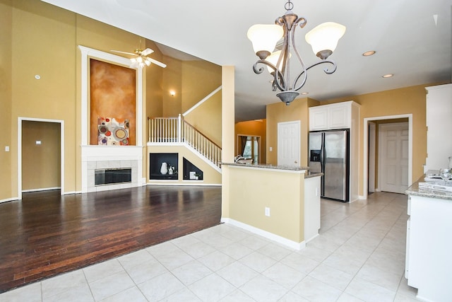 1623 Heddon Falls Dr, Sugar Land, TX 77479 - kitchen featuring stainless steel fridge, light tile patterned floors, a chandelier, white cabinetry, and light stone counters