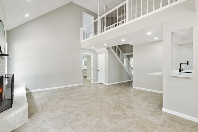 10007 Sagedowne Ln, Houston, TX 77089 - unfurnished living room with high vaulted ceiling, a brick fireplace, stairway, recessed lighting, and baseboards