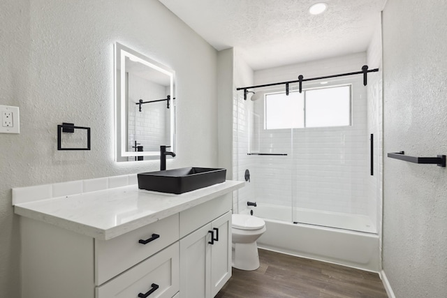 10007 Sagedowne Ln, Houston, TX 77089 - full bathroom with a textured wall, toilet, vanity, wood finished floors, and combined bath / shower with glass door