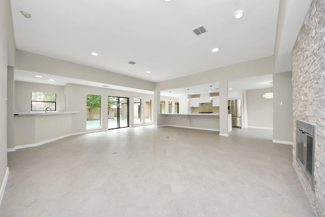 15707 Steamboat Ln, Houston, TX 77079 - unfurnished living room with a stone fireplace, baseboards, recessed lighting, and a sink