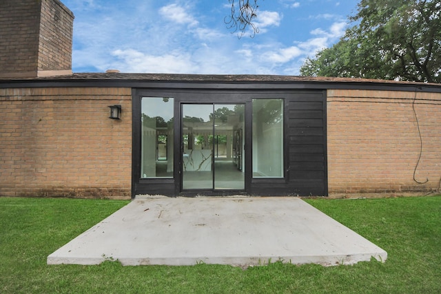 15707 Steamboat Ln, Houston, TX 77079 - view of exterior entry featuring a patio, a chimney, a yard, and brick siding