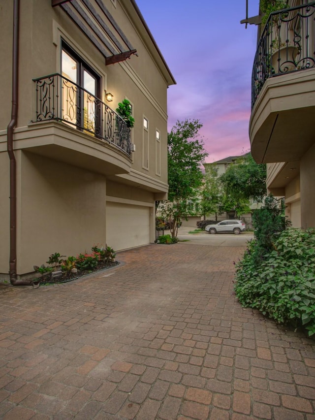 4310 Feagan St Unit A, Houston, TX 77007 - property exterior at dusk with a balcony, stucco siding, a garage, and decorative driveway