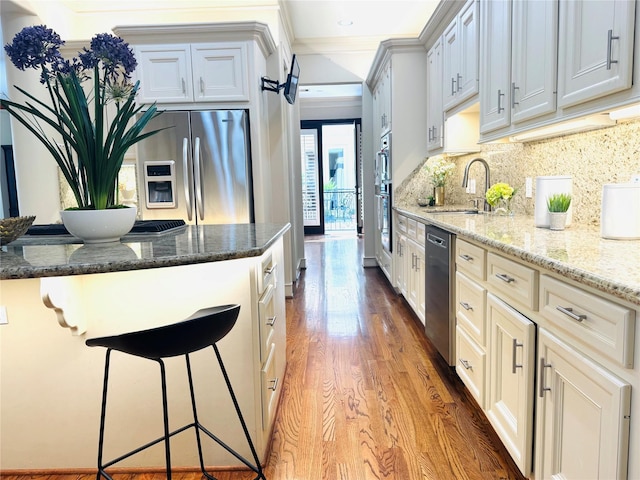 4310 Feagan St Unit A, Houston, TX 77007 - kitchen with stainless steel appliances, a sink, light wood-style floors, crown molding, and stone countertops