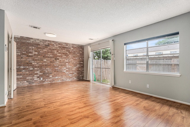 1145 Country Place Dr, Houston, TX 77079 - empty room featuring a textured ceiling, wood finished floors, brick wall, and baseboards
