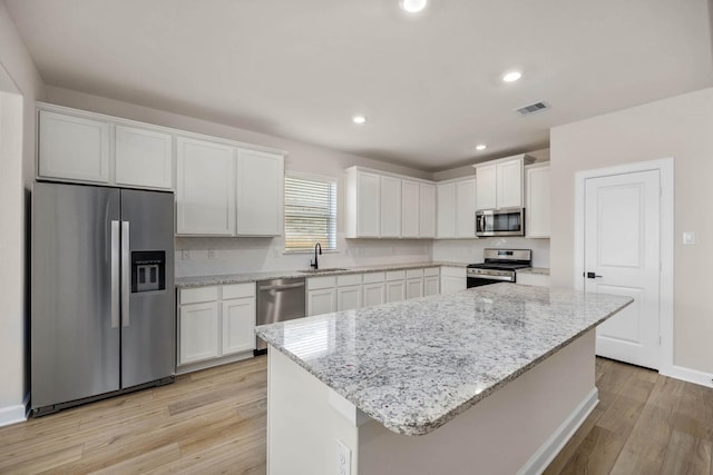 2921 Fair Wind Ln, Texas City, TX 77510 - kitchen with appliances with stainless steel finishes, a sink, white cabinets, light wood-type flooring, and recessed lighting