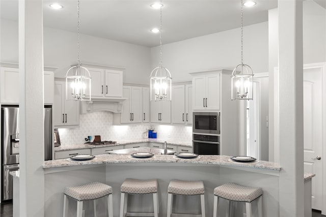 127 Evening Tide Ct, Conroe, TX 77318 - kitchen featuring appliances with stainless steel finishes, decorative backsplash, a chandelier, and a kitchen breakfast bar