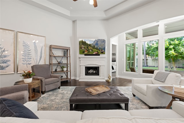127 Evening Tide Ct, Conroe, TX 77318 - living room featuring a ceiling fan, a fireplace with raised hearth, wood finished floors, a raised ceiling, and baseboards