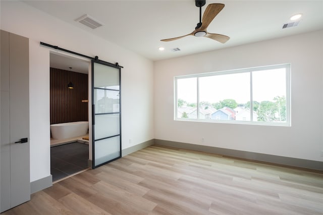 1053 W 15th 1/2 St, Houston, TX 77008 - unfurnished bedroom with a barn door, light wood finished floors, ceiling fan, and recessed lighting