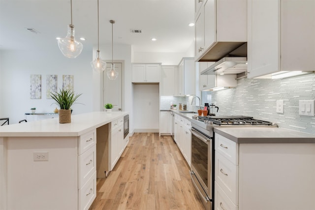 1414 Wichman St, Houston, TX 77007 - kitchen with appliances with stainless steel finishes, a sink, under cabinet range hood, light wood-type flooring, and backsplash