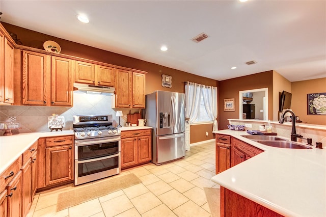 2714 San Marco Ln, League City, TX 77573 - kitchen with stainless steel appliances, a sink, under cabinet range hood, decorative backsplash, and light countertops