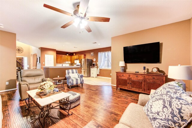 2714 San Marco Ln, League City, TX 77573 - living room featuring ceiling fan, baseboards, light wood-style flooring, stairs, and arched walkways