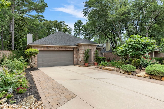 15 Prism Cove Pl, The Woodlands, TX 77381 - view of front of house with a chimney, brick siding, an attached garage, and driveway