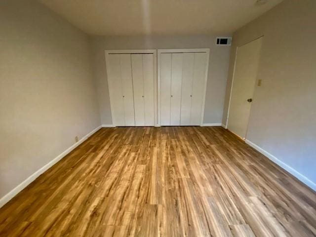 2121 Fountain View Dr Unit 8, Houston, TX 77057 - unfurnished bedroom featuring two closets, wood finished floors, and baseboards