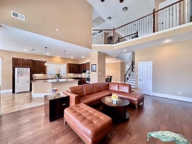 10410 Hatcher Dr, Katy, TX 77494 - living room featuring a high ceiling, stairway, baseboards, light wood-type flooring, and a ceiling fan