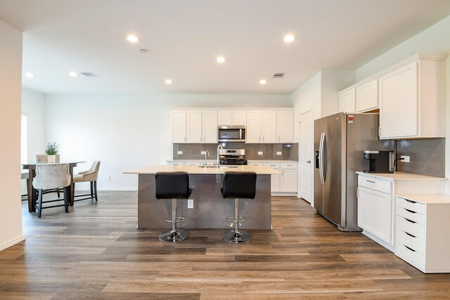 12324 Carib Crossing Ln, Conroe, TX 77304 - kitchen featuring stainless steel appliances, a kitchen breakfast bar, tasteful backsplash, an island with sink, and dark wood-style flooring