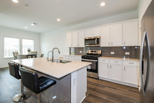 12324 Carib Crossing Ln, Conroe, TX 77304 - kitchen featuring appliances with stainless steel finishes, a sink, white cabinets, decorative backsplash, and dark wood finished floors