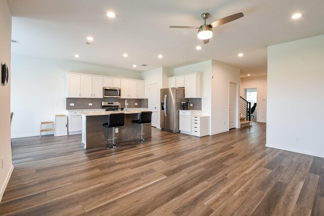 12324 Carib Crossing Ln, Conroe, TX 77304 - kitchen with appliances with stainless steel finishes, a ceiling fan, dark wood-style flooring, an island with sink, and white cabinets